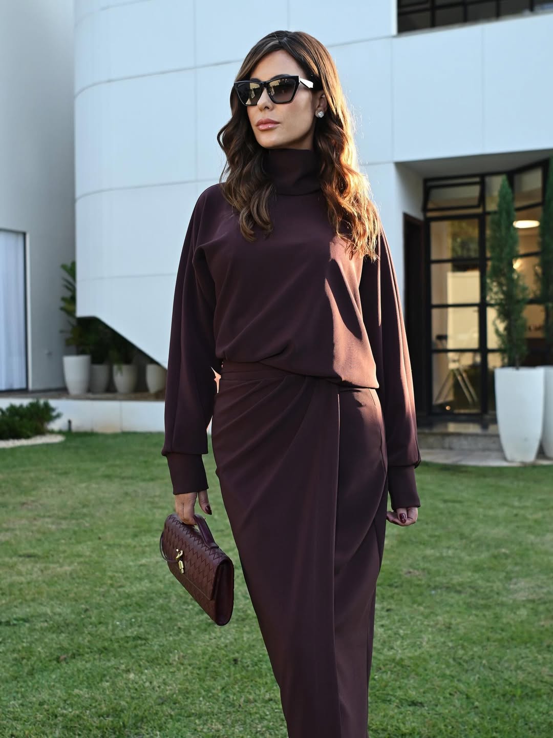 Mulher usando look AMMIS em tom vinho em ambiente externo.